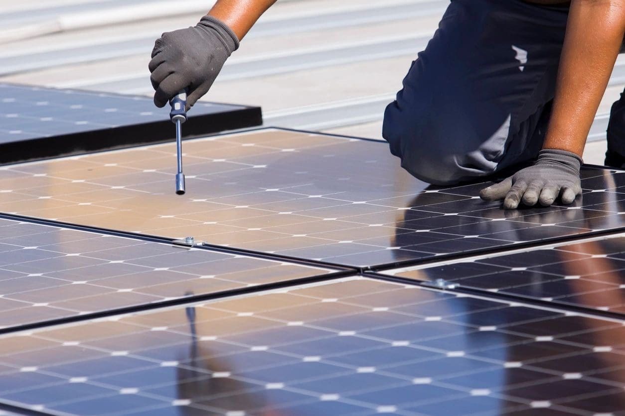 A person working on solar panels with a wrench.